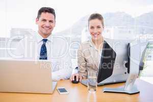 Smartly dressed colleagues using computer and laptop
