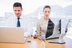 Smartly dressed colleagues using computer and laptop