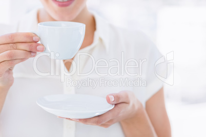Mid section of a businesswoman with tea cup