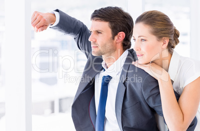 Smartly dressed business couple looking away in office