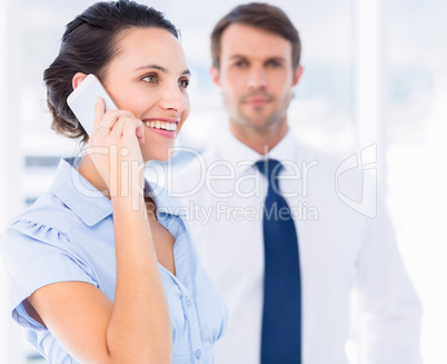 Woman on call with male colleague in background