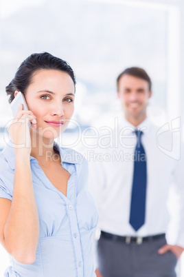 Woman on call with male colleague in background