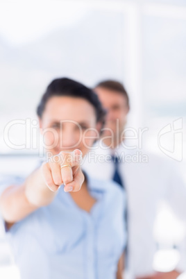 Woman pointing at camera with colleague in background