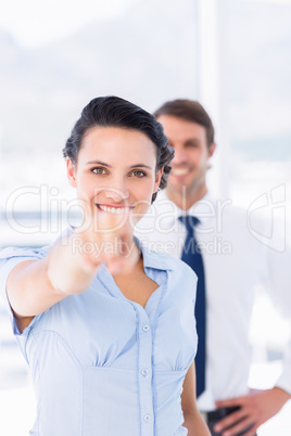 Woman pointing at camera with colleague in background