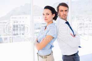 Young business couple standing with arms crossed