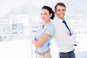 Smiling young business couple with arms crossed