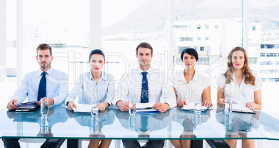 Smartly dressed executives sitting in row at desk