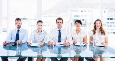 Smartly dressed executives sitting in row at desk