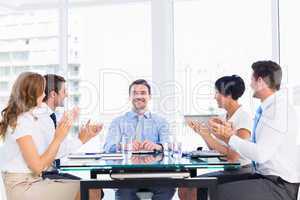 Executives clapping around conference table