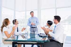 Executives clapping around conference table
