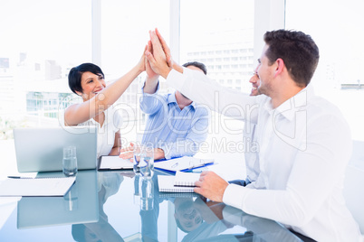 Executives giving high five in a business meeting