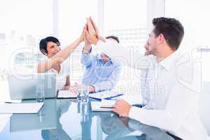 Executives giving high five in a business meeting