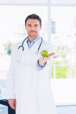 Portrait of a smiling male doctor holding an apple