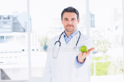 Portrait of a smiling male doctor holding an apple