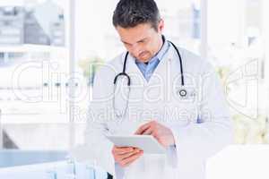 Concentrated male doctor using digital tablet