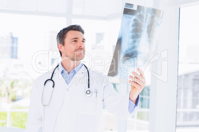 Serious male doctor examining x-ray