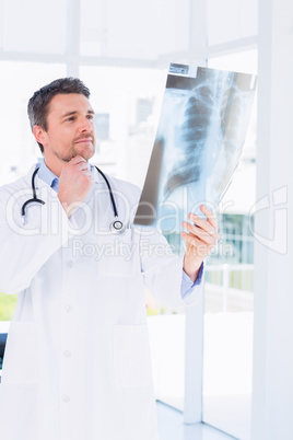 Serious male doctor examining x-ray