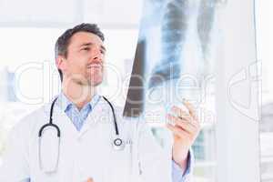 Serious male doctor examining x-ray