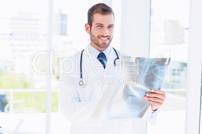 Portrait of a smiling young male doctor examining x-ray