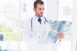 Concentrated young male doctor examining x-ray