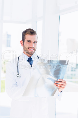 Portrait of a smiling young male doctor examining x-ray