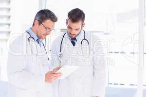 Male doctors using digital tablet in medical office