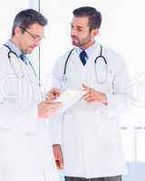 Male doctors using digital tablet in medical office