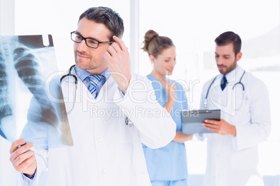Male doctor examining x-ray with colleagues behind