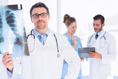 Male doctor examining x-ray with colleagues behind