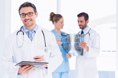 Doctor holding reports with colleagues examining x-ray