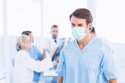 Male surgeon wearing mask with colleagues in meeting