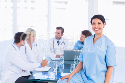 Smiling female surgeon with colleagues in meeting