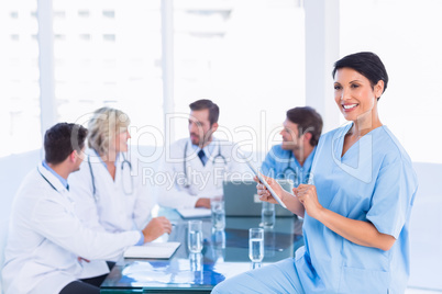 Female surgeon using digital tablet with colleagues in meeting