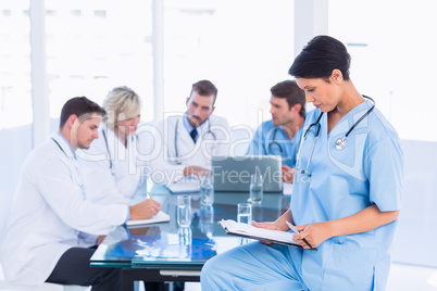 Female surgeon looking at reports with colleagues in meeting