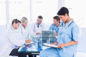 Female surgeon looking at reports with colleagues in meeting