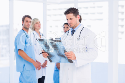 Doctor examining x-ray with colleagues standing behind