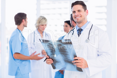 Doctor examining x-ray with colleagues standing behind