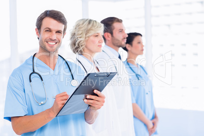 Male doctor writing reports with colleagues in medical office