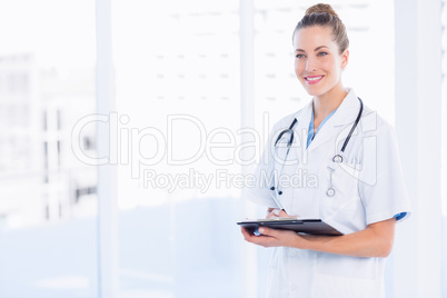 Confident female doctor with clipboard in hospital