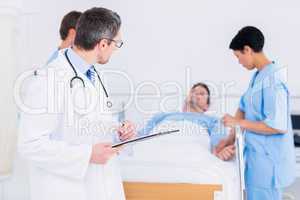 Doctor holding reports with patient and surgeon in background