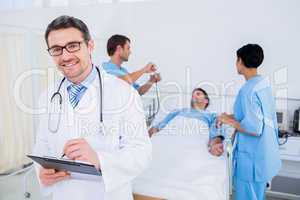 Doctor writing reports with patient and surgeons in background