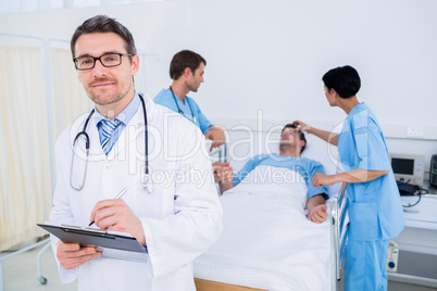 Doctor writing reports with patient and surgeons in background