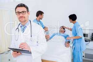 Doctor writing reports with patient and surgeons in background