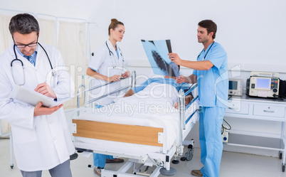 Doctors holding reports by patient in at hospital