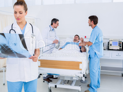 Doctor examining x-ray with colleagues and patient in hospital