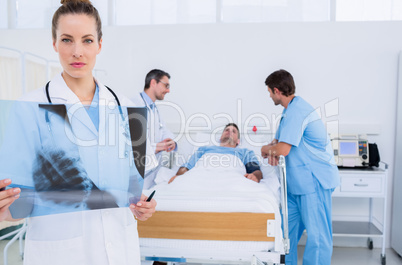 Doctor holding x-ray with colleagues and patient in hospital