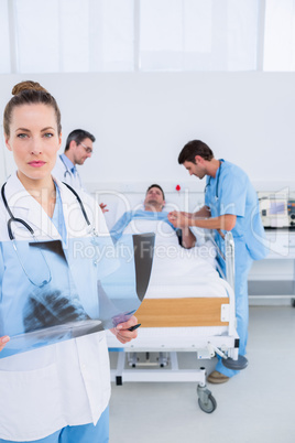 Doctor holding x-ray with colleagues and patient in hospital