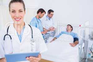 Doctor using digital tablet with colleagues and patient behind