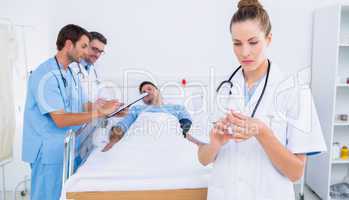 Doctor holding a syringe with colleagues and patient in hospital