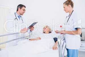 Doctors visiting a female patient in hospital